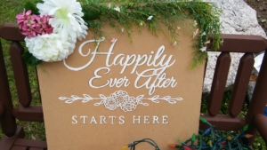 A sign that says "Happily Ever After Starts Here', decorated for a wedding.