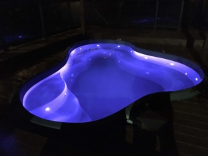 An image of Footprints Resort Ontario's new pool at night, lit from below with blue light.